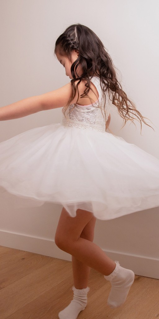 Child twirling in a white dress during a family portrait session