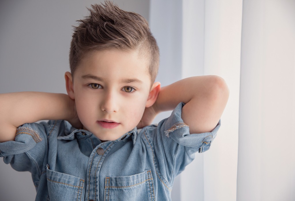 Young boy in a denim shirt photographed in a bright studio