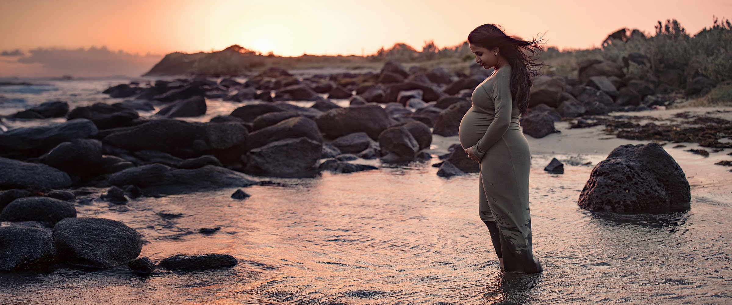 Maternity portrait at sunset on a beach with warm natural light