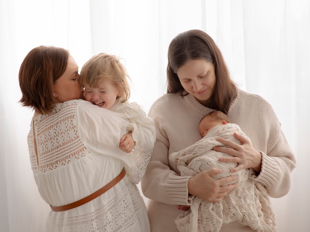 Family with newborn baby and toddler in soft studio light