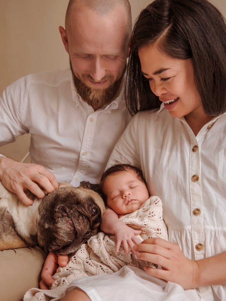 Parents with newborn baby and family dog during an in-home portrait session