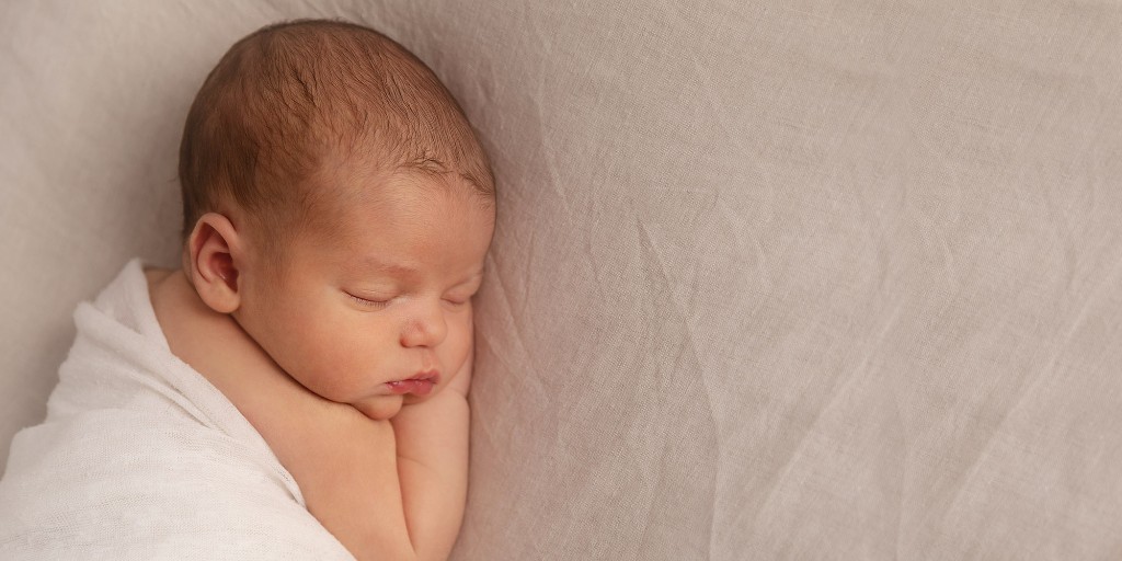 Newborn portrait with parents in a softly lit bedroom