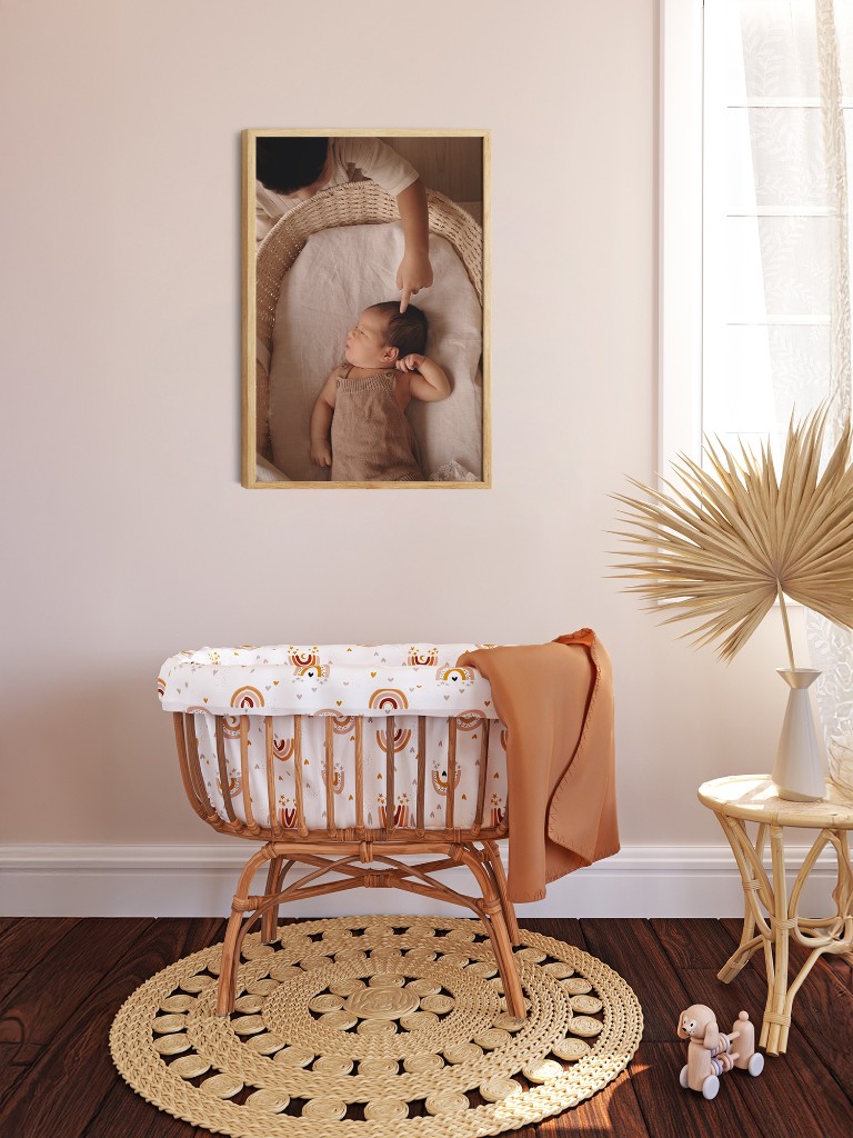 Framed newborn portrait artwork displayed in a nursery setting