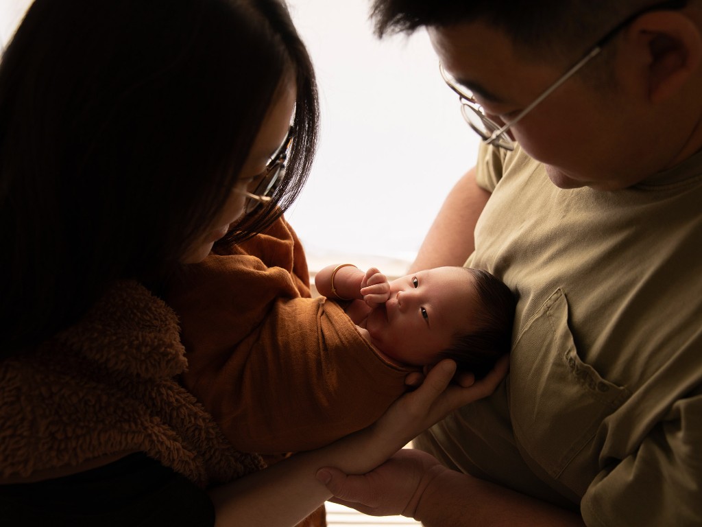 Parents holding their newborn baby in soft natural light